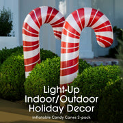 Inflatable candy canes with red and white stripes in front of a house.